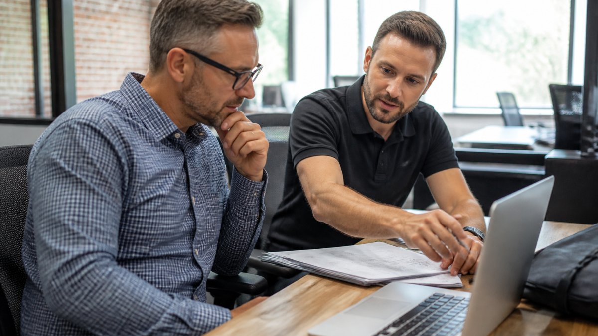 Which Managed IT Services Work Best for Small Business? 1 Small business owner and IT technician reviewing managed IT services on a dashboard in a modern office